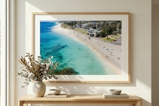 Framed beach scene on a wall above a console table with decor items.