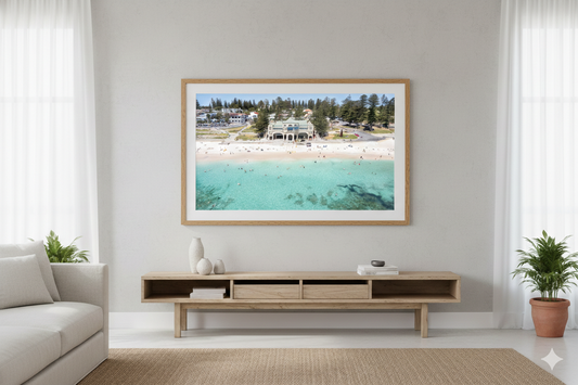 Framed beach scene print on a wall above a television stand in a living room.