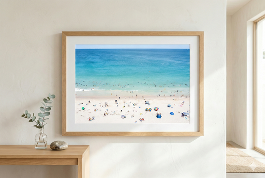 Framed beach scene print on a wall with a wooden frame