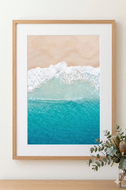 Framed artwork of a beach scene with waves on a wall.