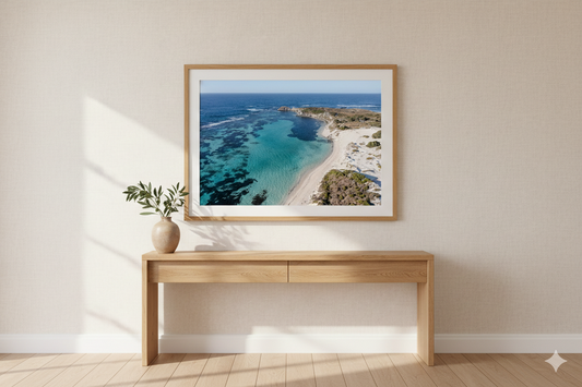 Framed artwork of a beach scene above a wooden console table in a room with a neutral color scheme.