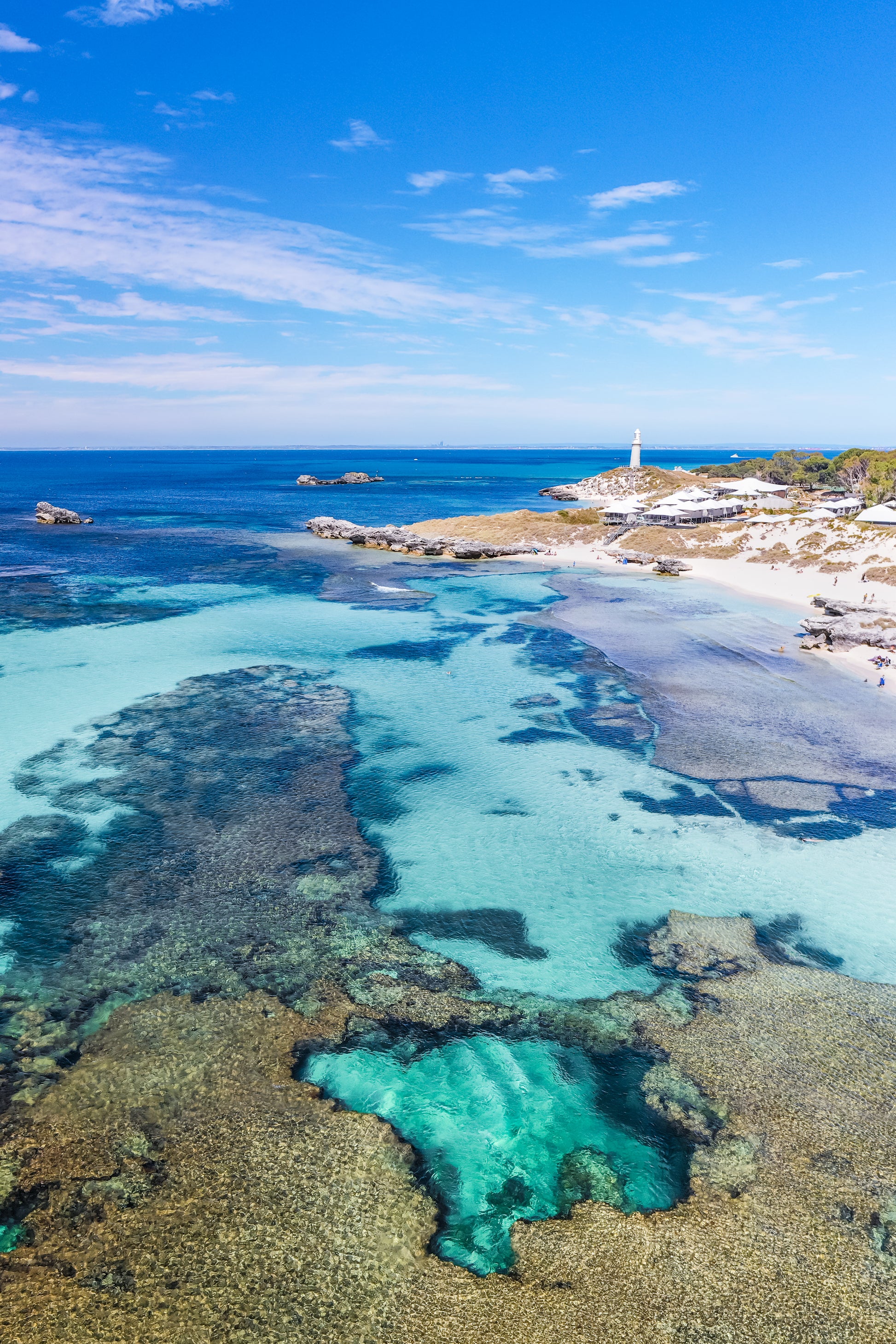 Clear turquoise waters with a rocky coastline and blue sky.