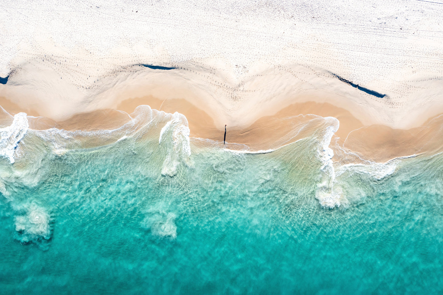 Aerial view of a beach with waves crashing onto the shore.