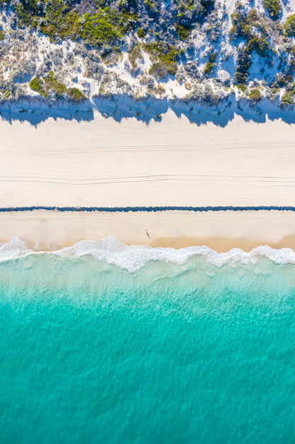 Top-down view of a beach with turquoise water and white sand.