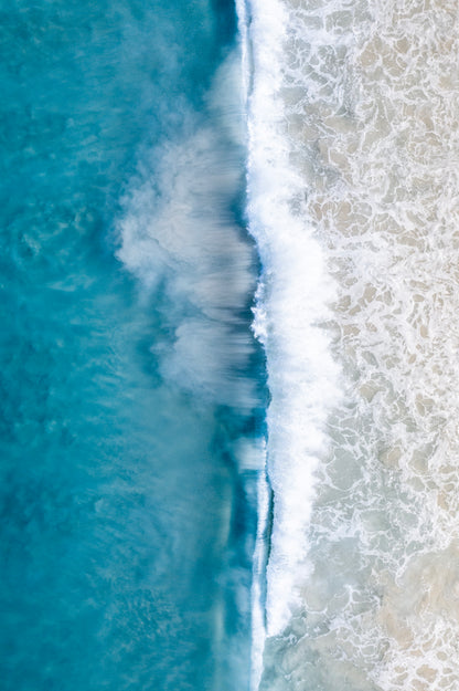 Top-down view of ocean waves crashing onto a beach