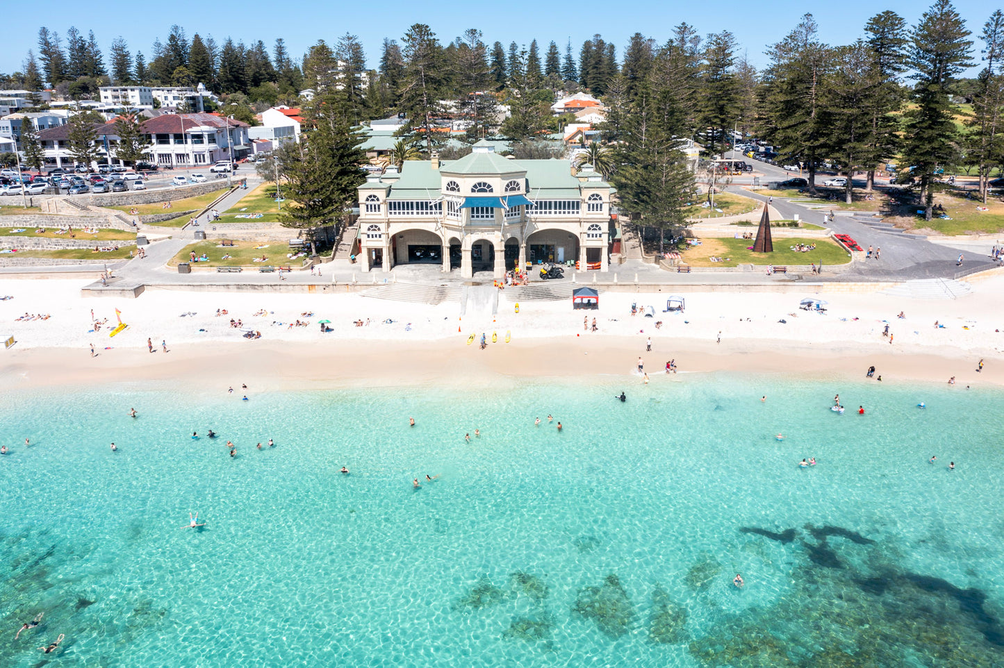 Aerial view of a beach with clear blue water and a building in the background.