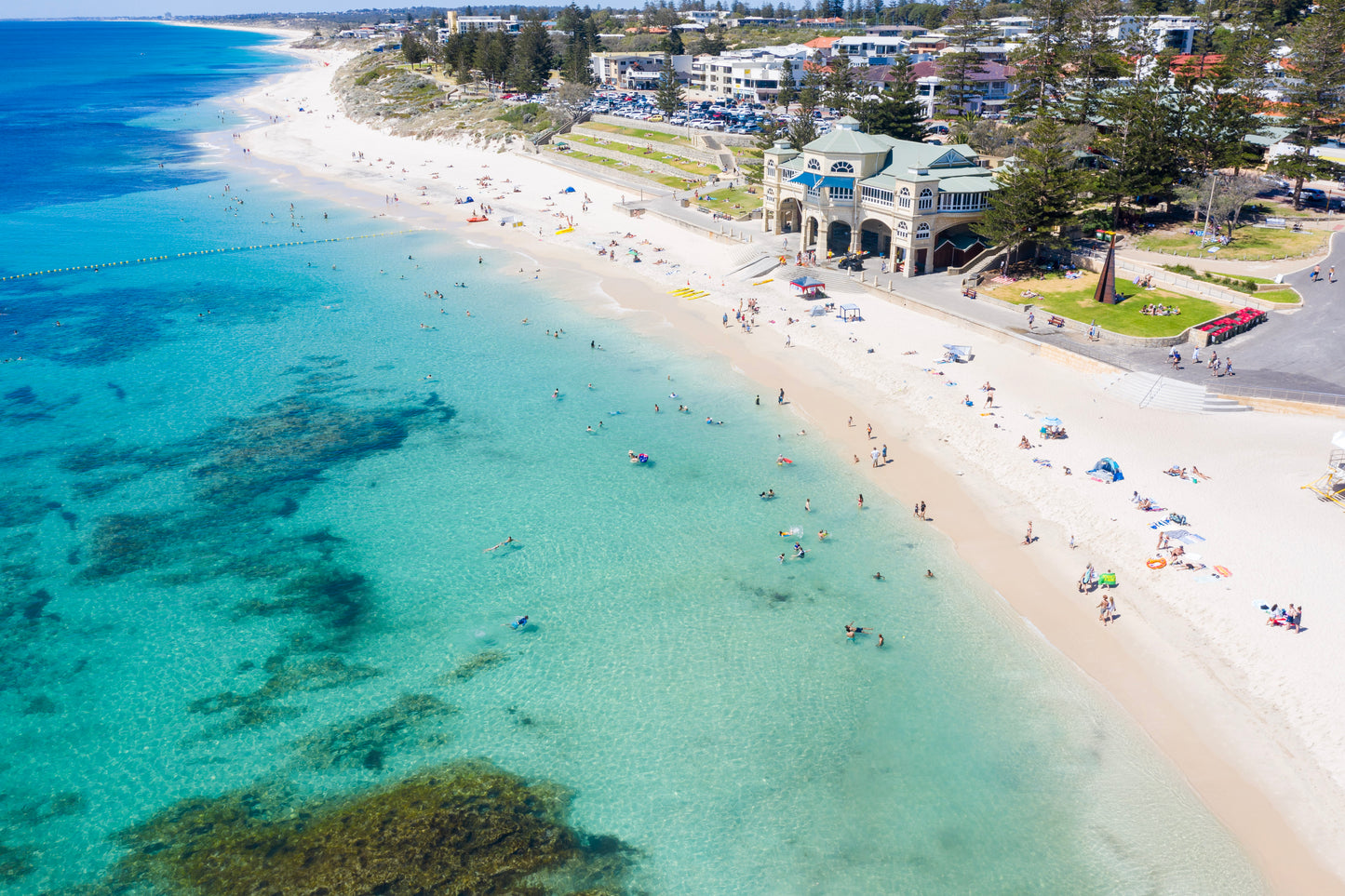 Aerial view of a beach with clear blue water and a building on the shore.