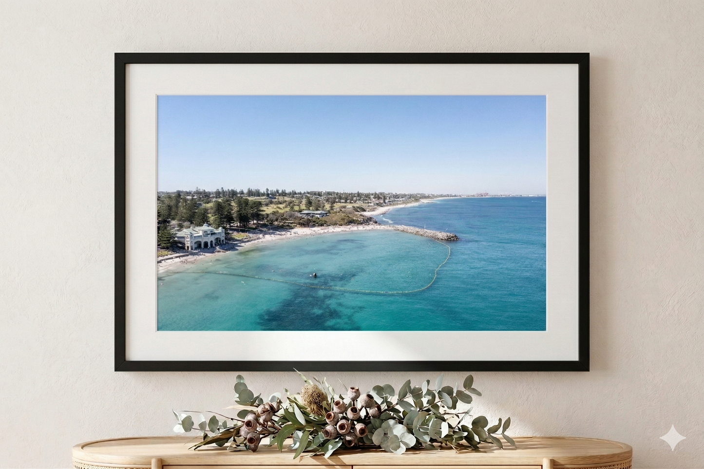 Framed photograph of a coastal scene with clear blue water and a beach.