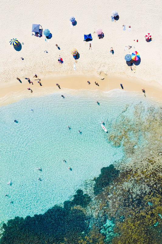 Aerial view of Cottesloe beach with people, umbrellas, and clear blue water.