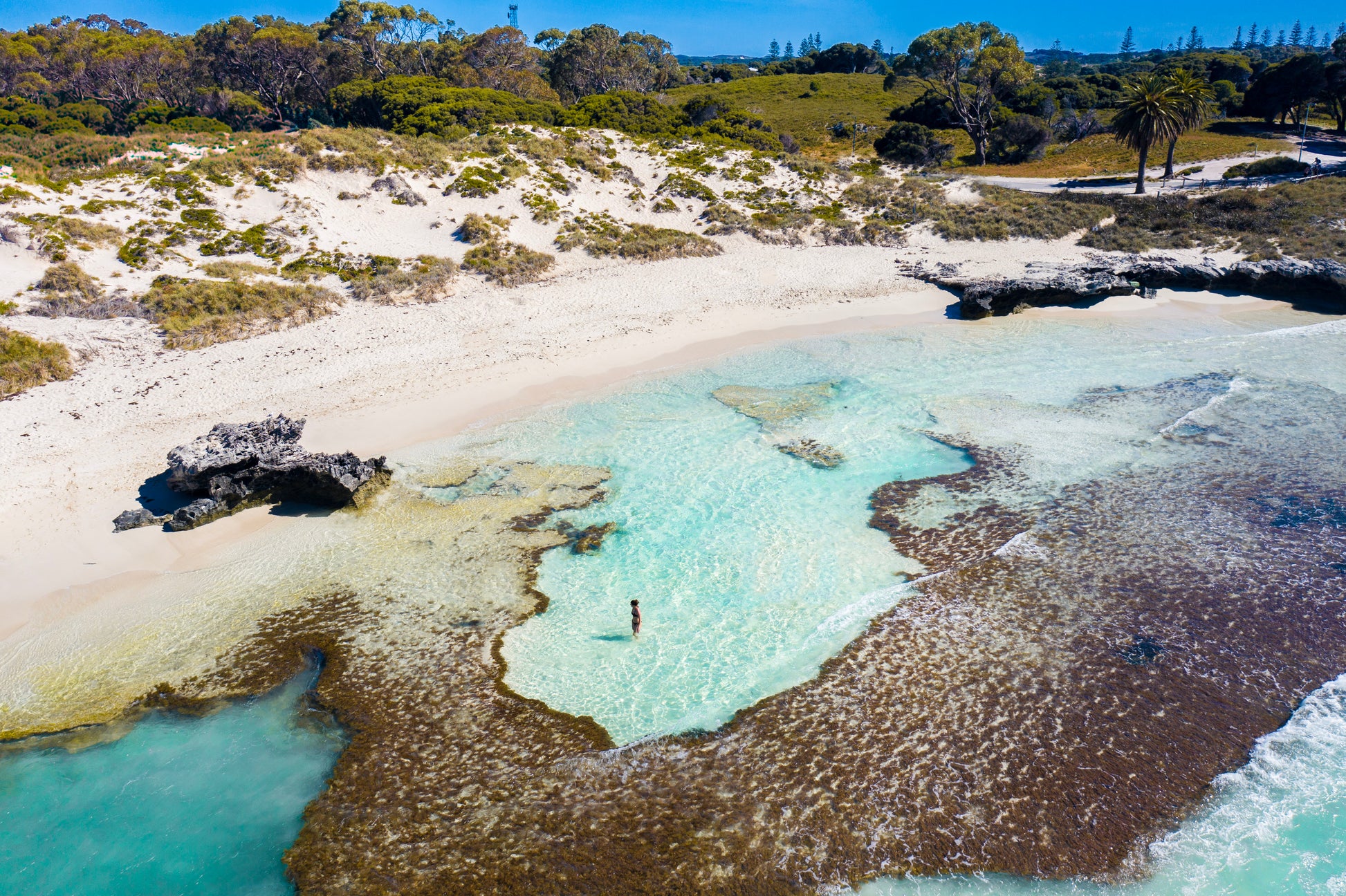 Aerial view of a beach with clear blue water and white sand.