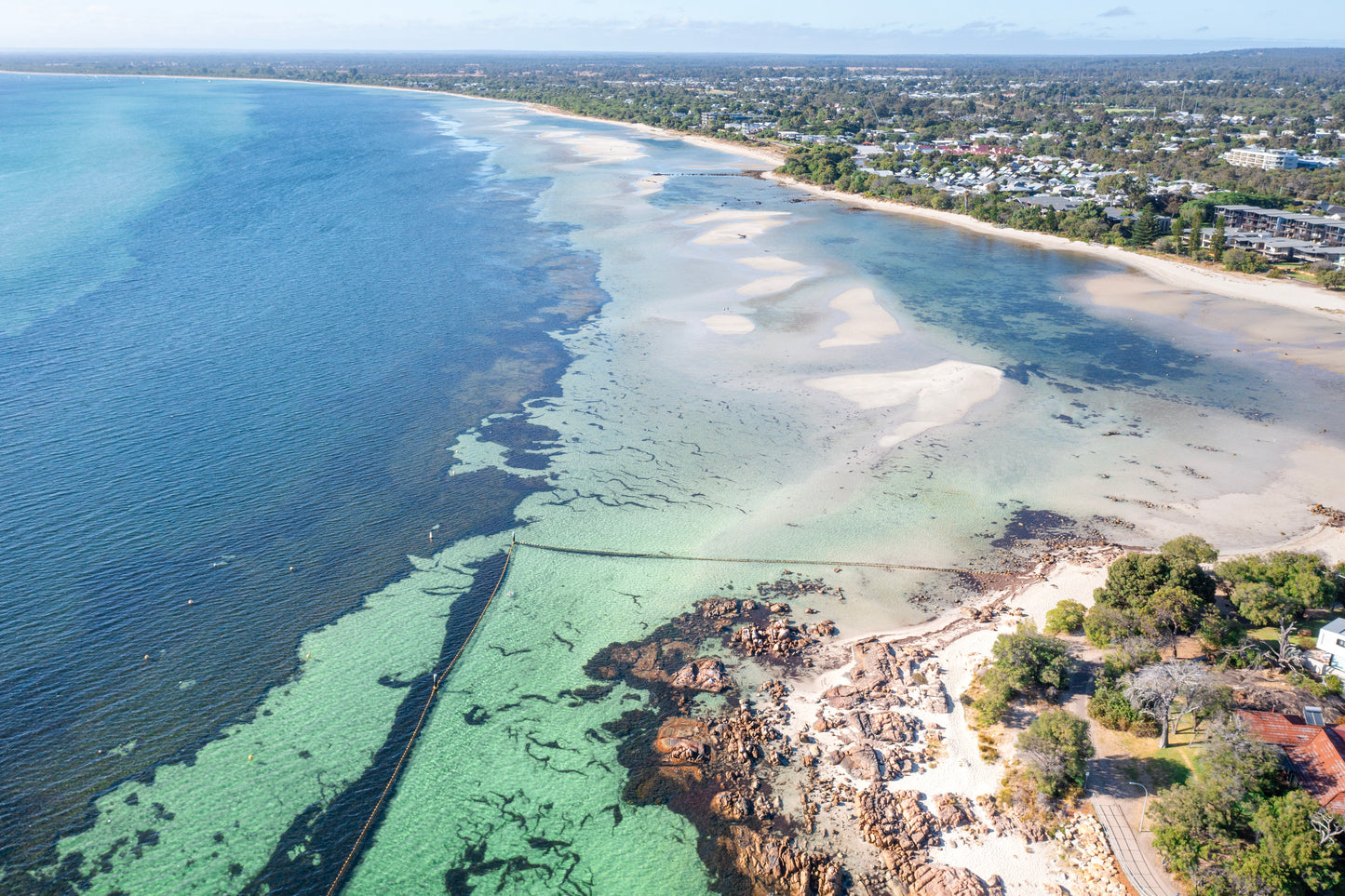 Aerial view of a coastal area with clear blue water and a beach.