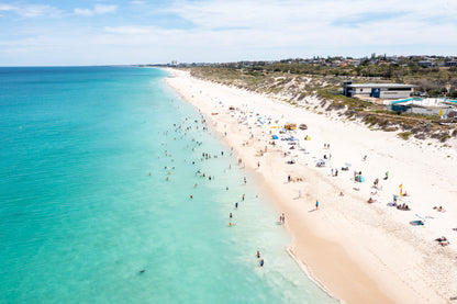 Beach scene with clear blue water and white sand, people enjoying the beach.