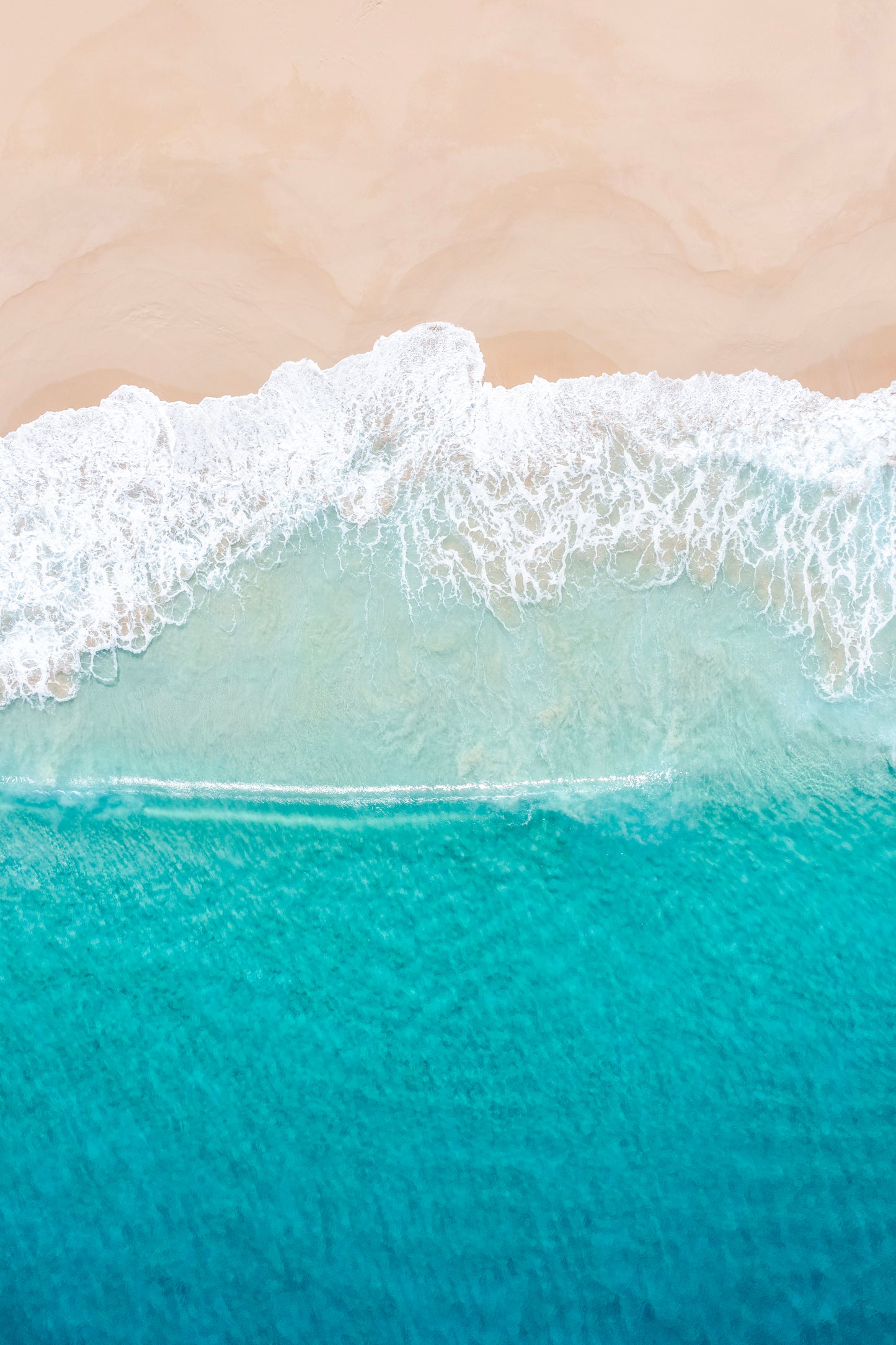 Close-up of ocean waves meeting a sandy beach