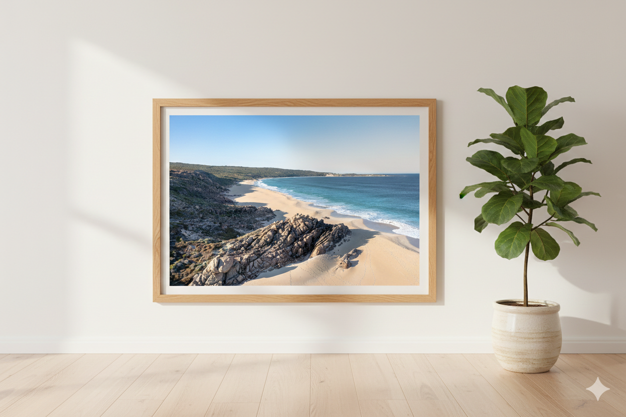 Framed photograph of a beach scene on a wall next to a potted plant.