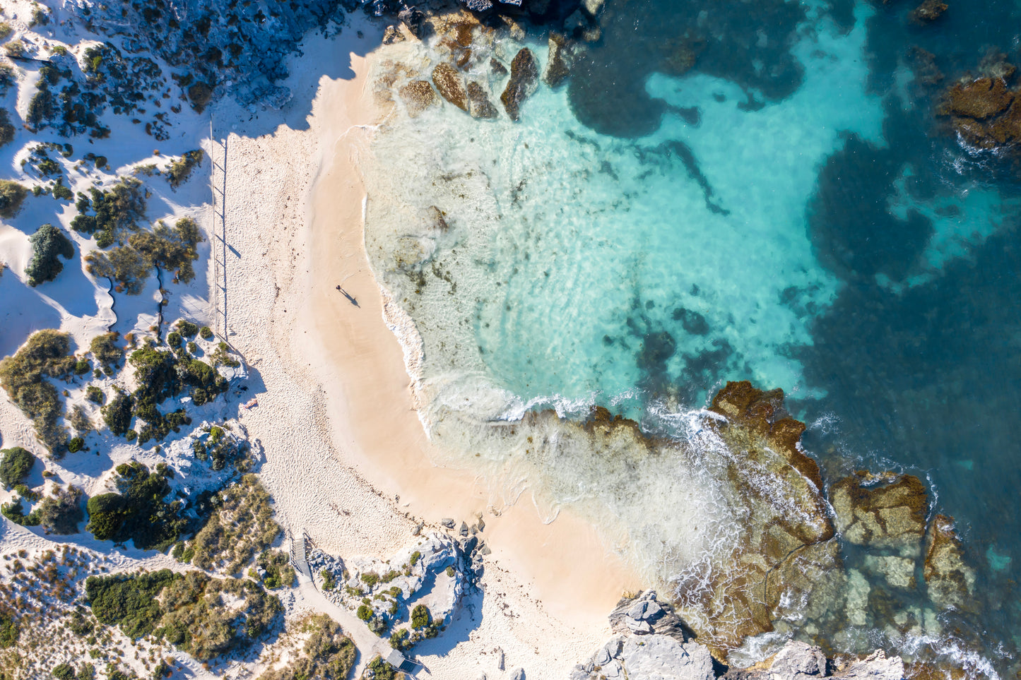 Aerial view of a natural pool with clear water surrounded by rocks and vegetation.