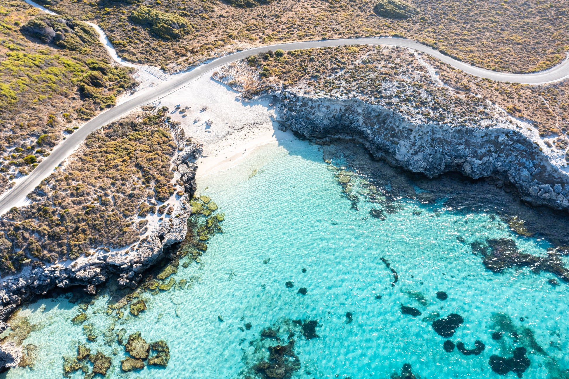 Aerial view of a coastal landscape with clear blue water and rocky shoreline.