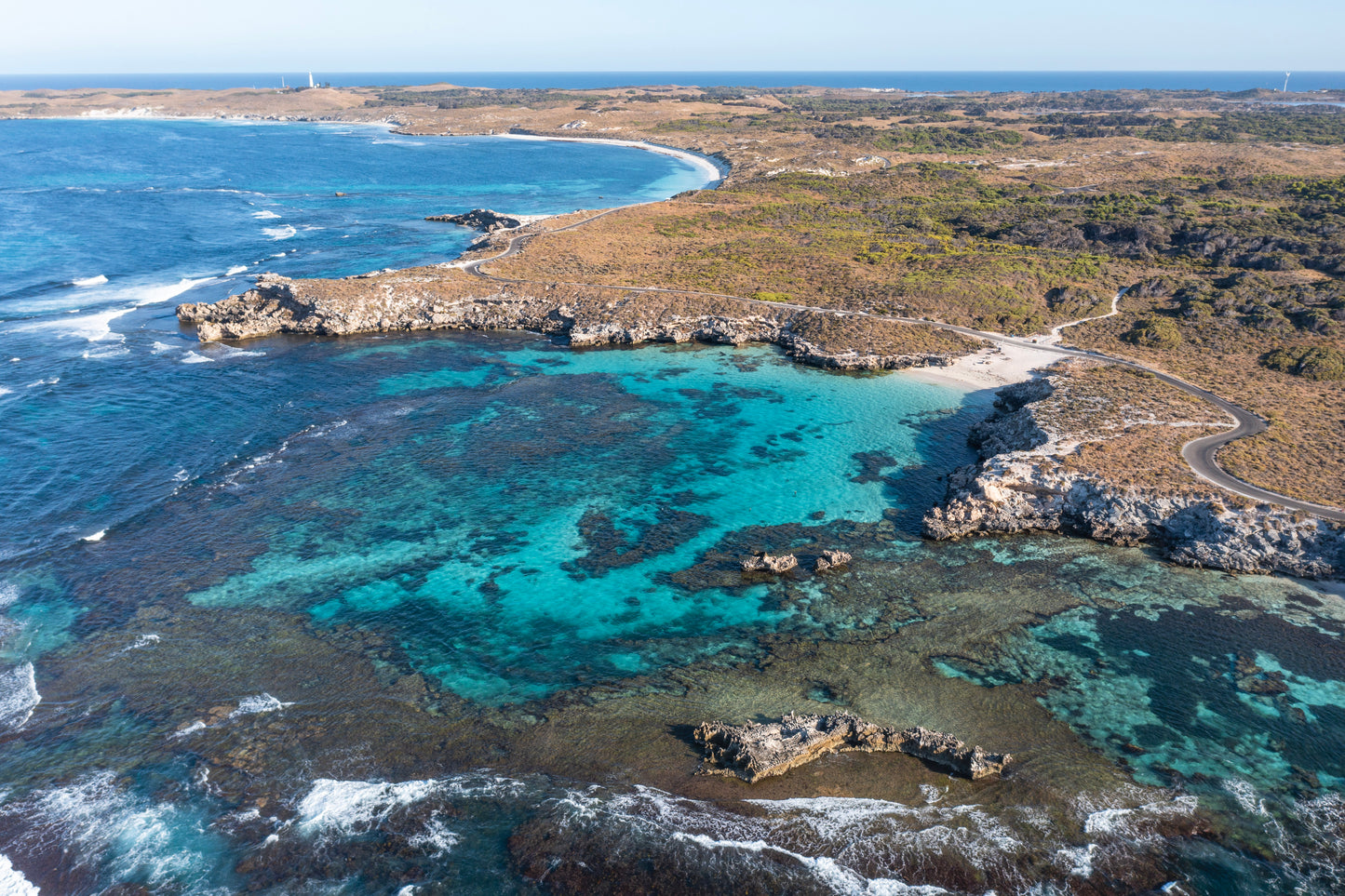 Aerial view of a coastal landscape with clear blue waters and rocky shores.