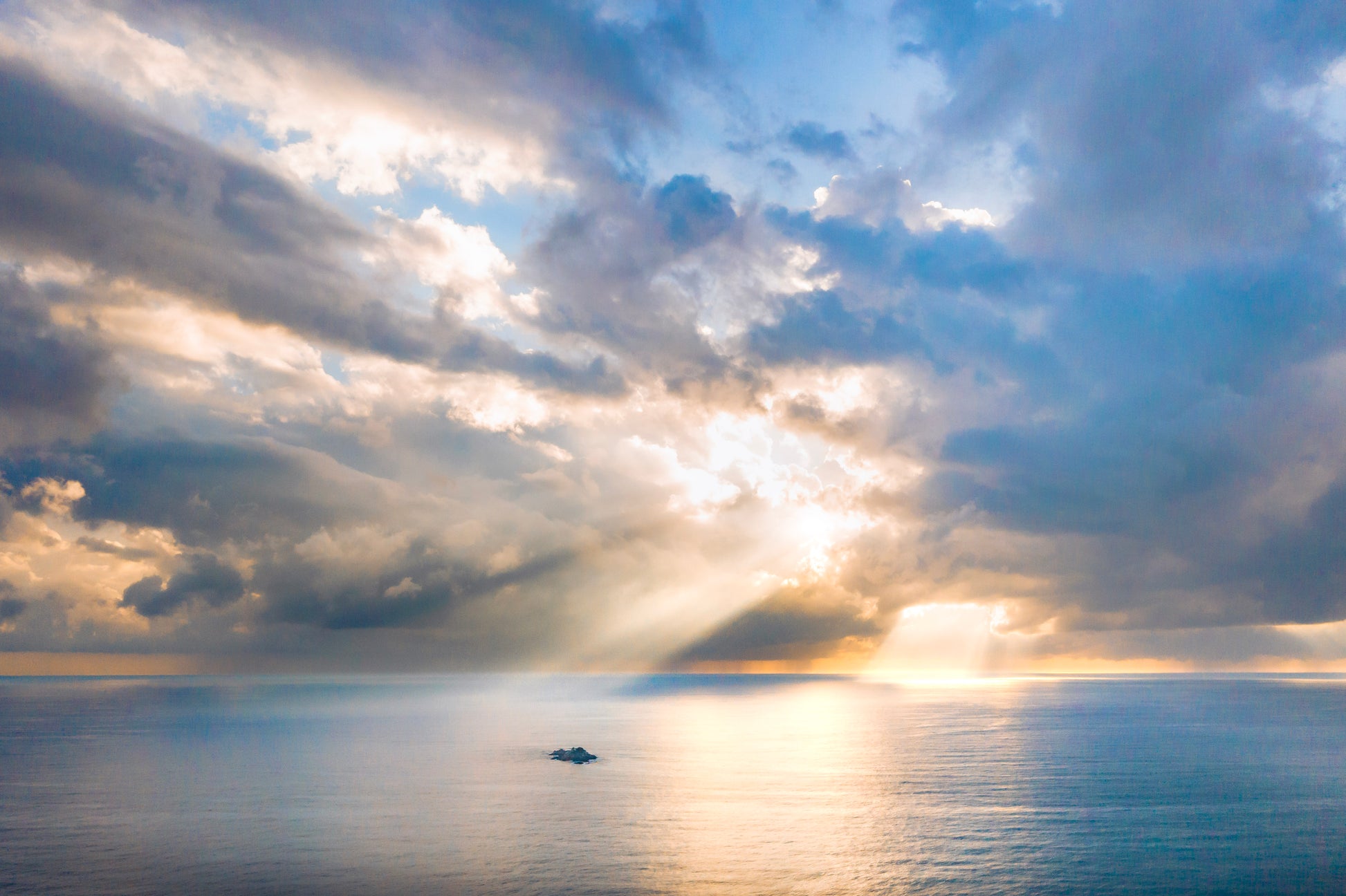 Sunlight breaking through clouds over a calm ocean