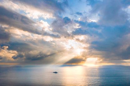 Sunlight breaking through clouds over a calm ocean