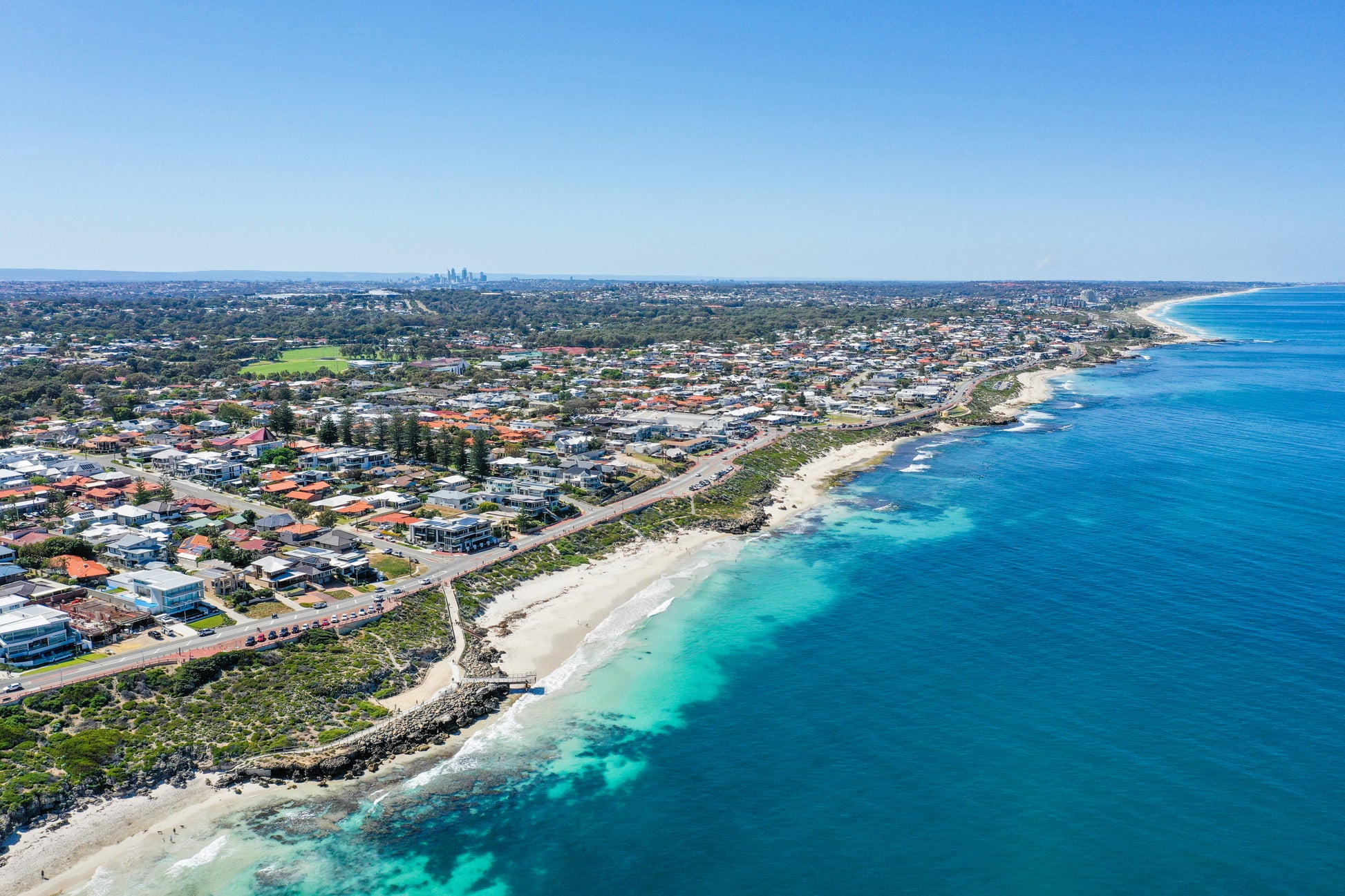 Aerial view of a coastal town with clear blue water and a blue sky.