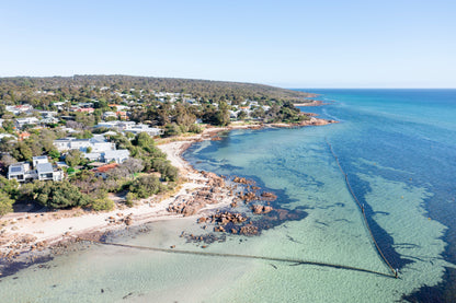 A coastal area with houses, a beach, and clear blue water.