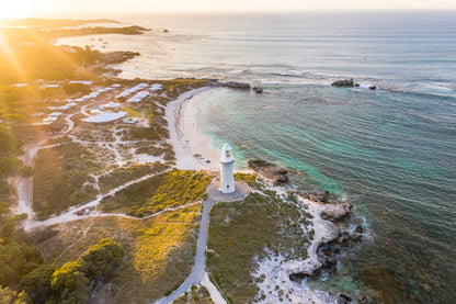 Lighthouse on a rocky island with a clear sky and sun.