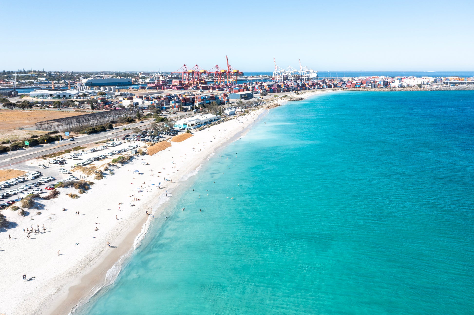 Aerial view of a coastal area with a beach and shipping containers.