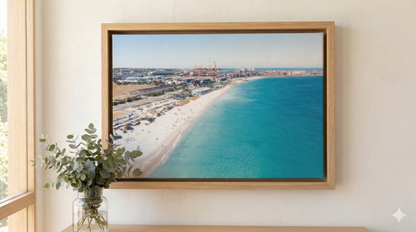 Framed photograph of a beach scene on a wall with a plant to the left.