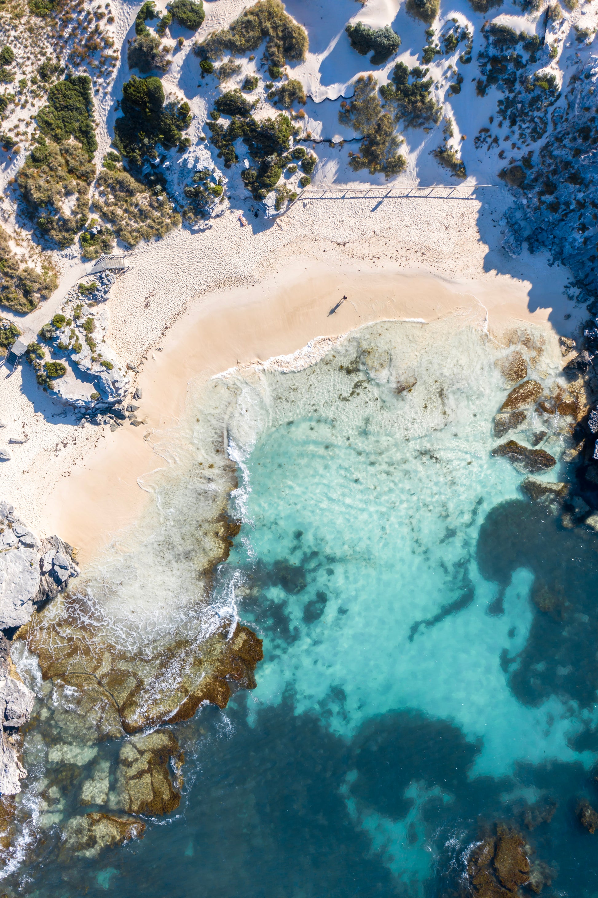 Aerial view of a coastal area with clear blue water and rocky shoreline.