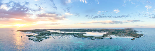 Panorama of Rottnest Island at sunset, showing the island and surrounding ocean with a colorful sky.