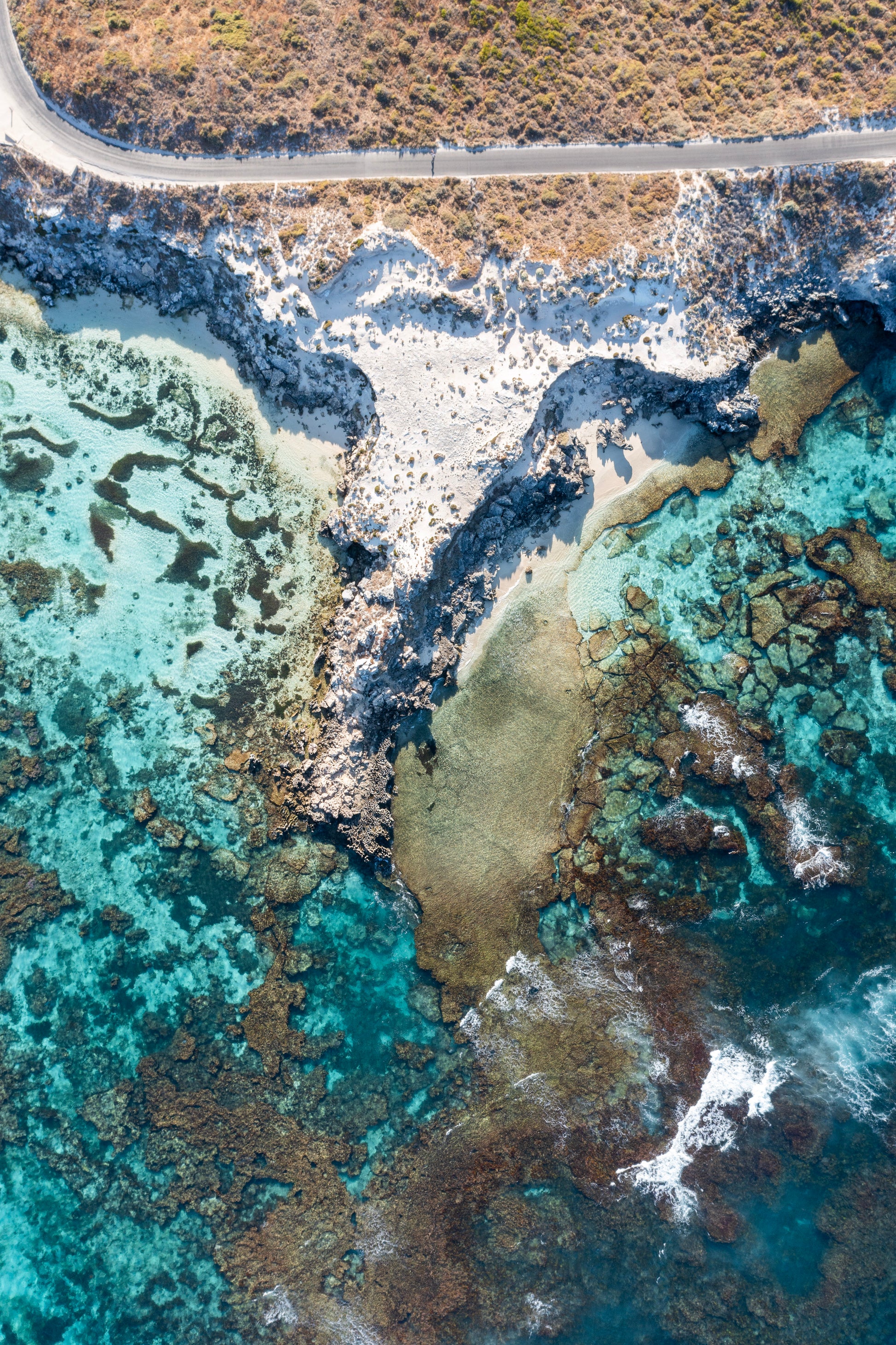 Aerial view of a coastal landscape with turquoise waters and rocky shore.
