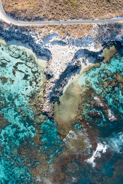 Aerial view of a coastal landscape with turquoise waters and rocky shore.