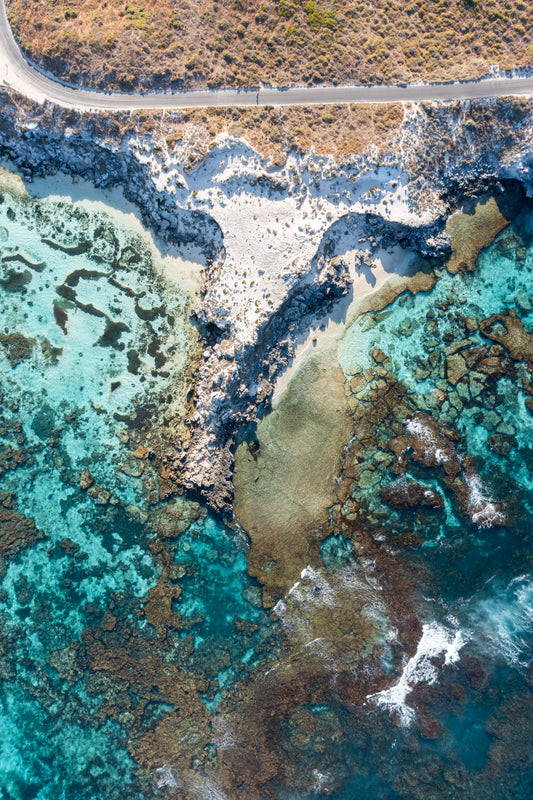 Aerial view of a coastal landscape with turquoise waters and rocky shore.
