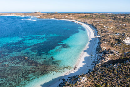Aerial view of a beach with clear blue water and a small island in the distance.