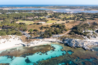 Aerial view of a coastal landscape with greenery, water bodies, and a road.