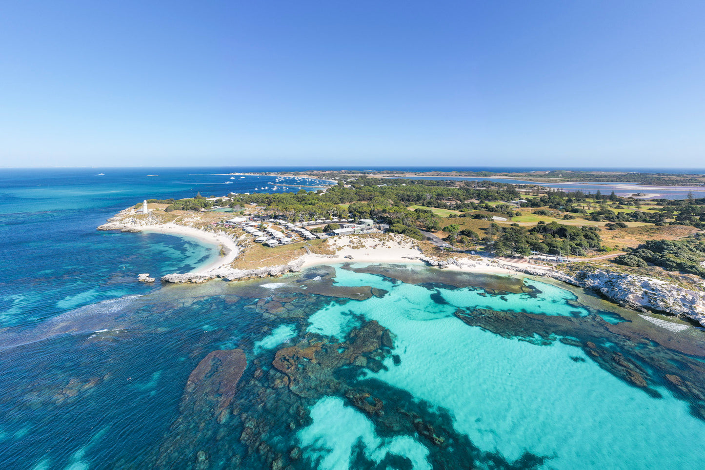 Aerial view of a coastal area with turquoise waters and a clear blue sky.