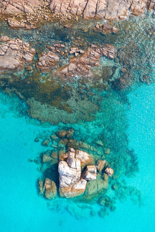 A vibrant underwater scene with various colors and rock formations, framed within a solid wooden structure with a clear glass cover.